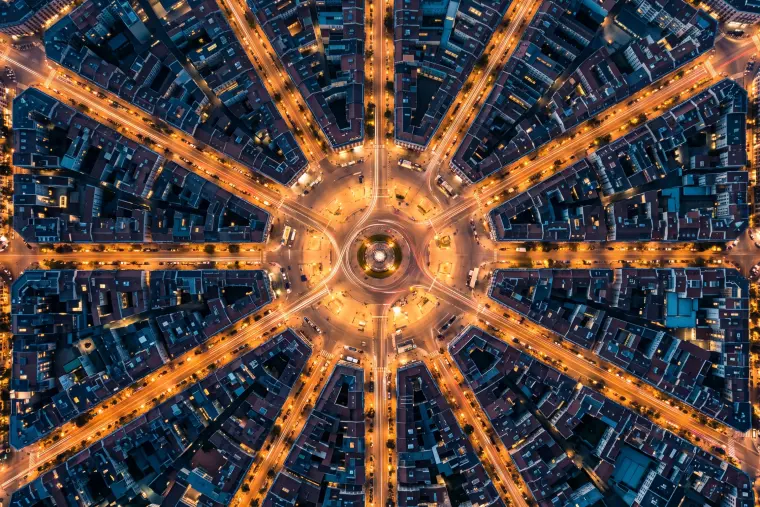 Aerial night view of a circular city square with illuminated avenues radiating out like the spokes of a wheel.